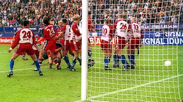 
                <strong>Treffer ins Schalker Herz</strong><br>
                Dieses Last-Minute-Tor zum 1:1 des FC Bayern beim HSV tut besonders den Schalkern weh. Denn bei einer Niederlage der Münchner an diesem letzten Spieltag der Saison 2000/2001 wären die "Knappen" Meister gewesen. Weil der verhängnisvolle Freistoß-Pfiff von Markus Merk umstritten ist, wird der Schiri auf Schalke zum Hassbild.
              