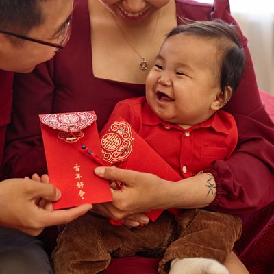 Portrait of happy Asian family with cute baby boy enjoying Chinese New Year celebration at home and holding red envelopes Have overflowing abundance every year