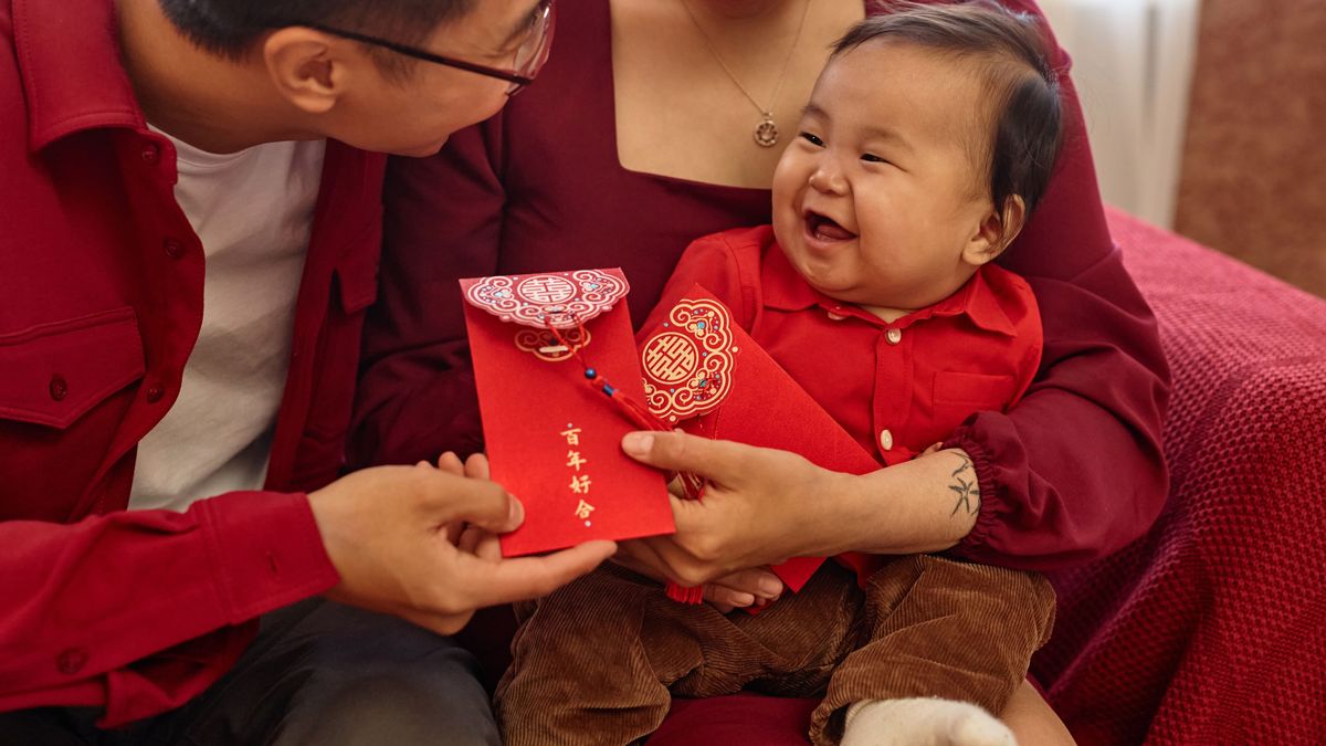 Portrait of happy Asian family with cute baby boy enjoying Chinese New Year celebration at home and holding red envelopes Have overflowing abundance every year