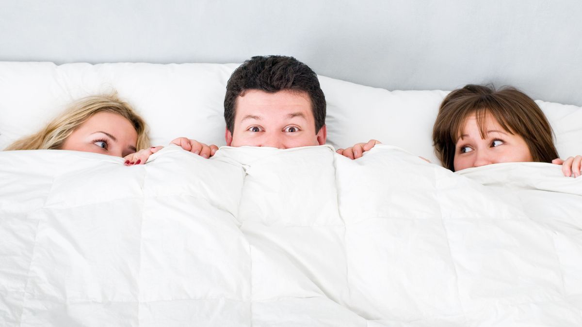 Mann im Bett mit 2 Frauen