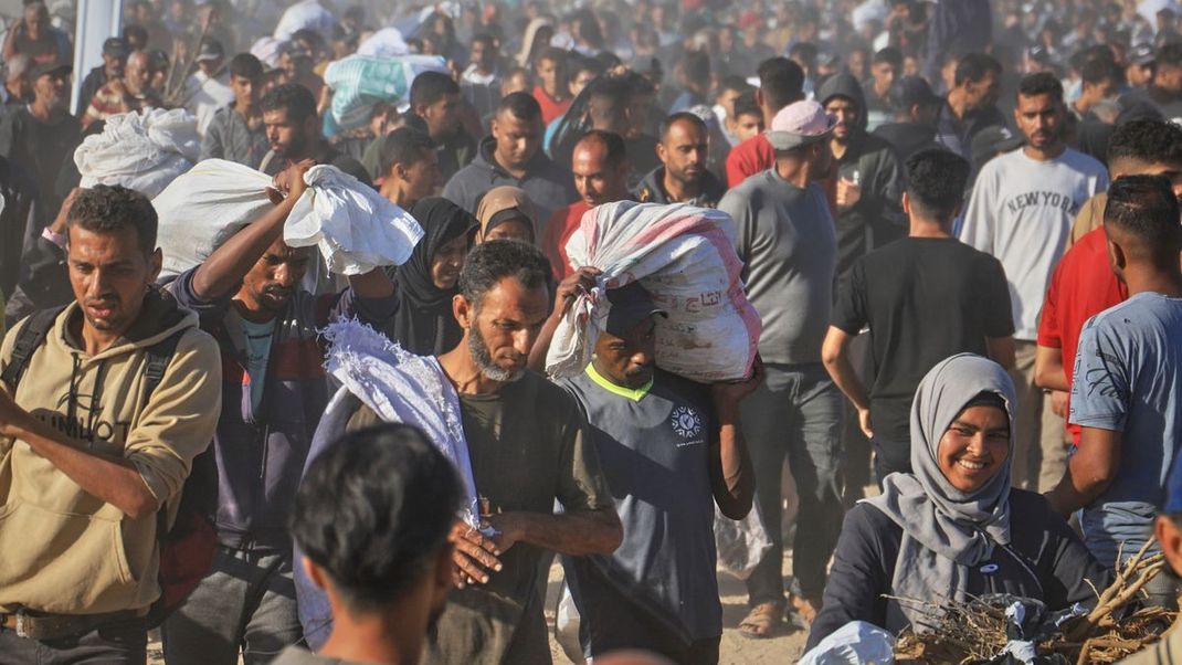 Palästinenser:innen versorgen sich bei der Nahrungsmittelverteilung - seit Mai sollen dabei 410 Menschen durch israelische Angriffe ums Leben gekommen sein.