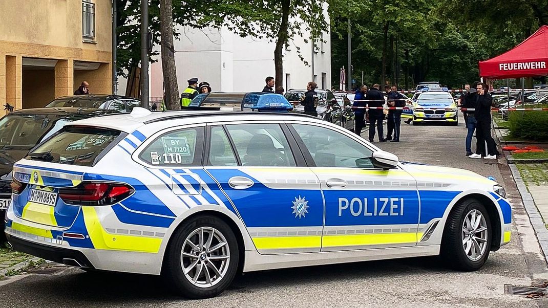 Einsatzkräfte der Polizei stehen vor einem Mehrfamilienhaus im Stadtteil Milbertshofen.