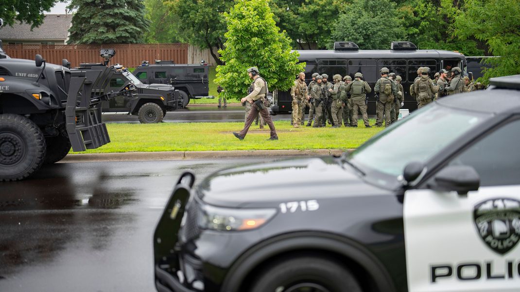 Beamte der Strafverfolgungsbehörden, darunter die örtliche Polizei, Sheriffs und das FBI, stehen weniger als eine Meile vom Unglücksort in Brooklyn Park, Minnesota entfernt.