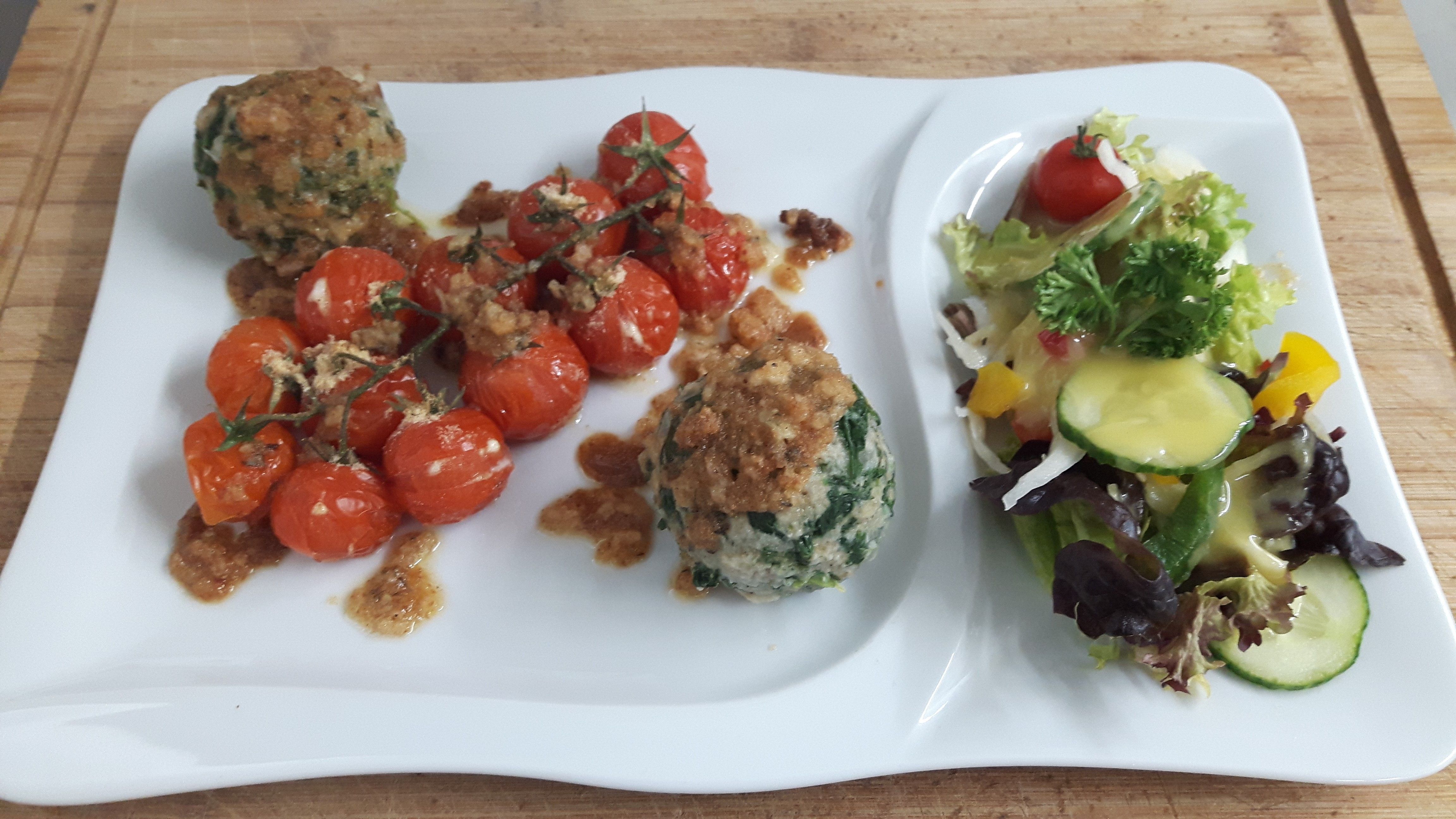 Spinatknödel auf geschmolzenen Tomaten mit zerlassener Butter
