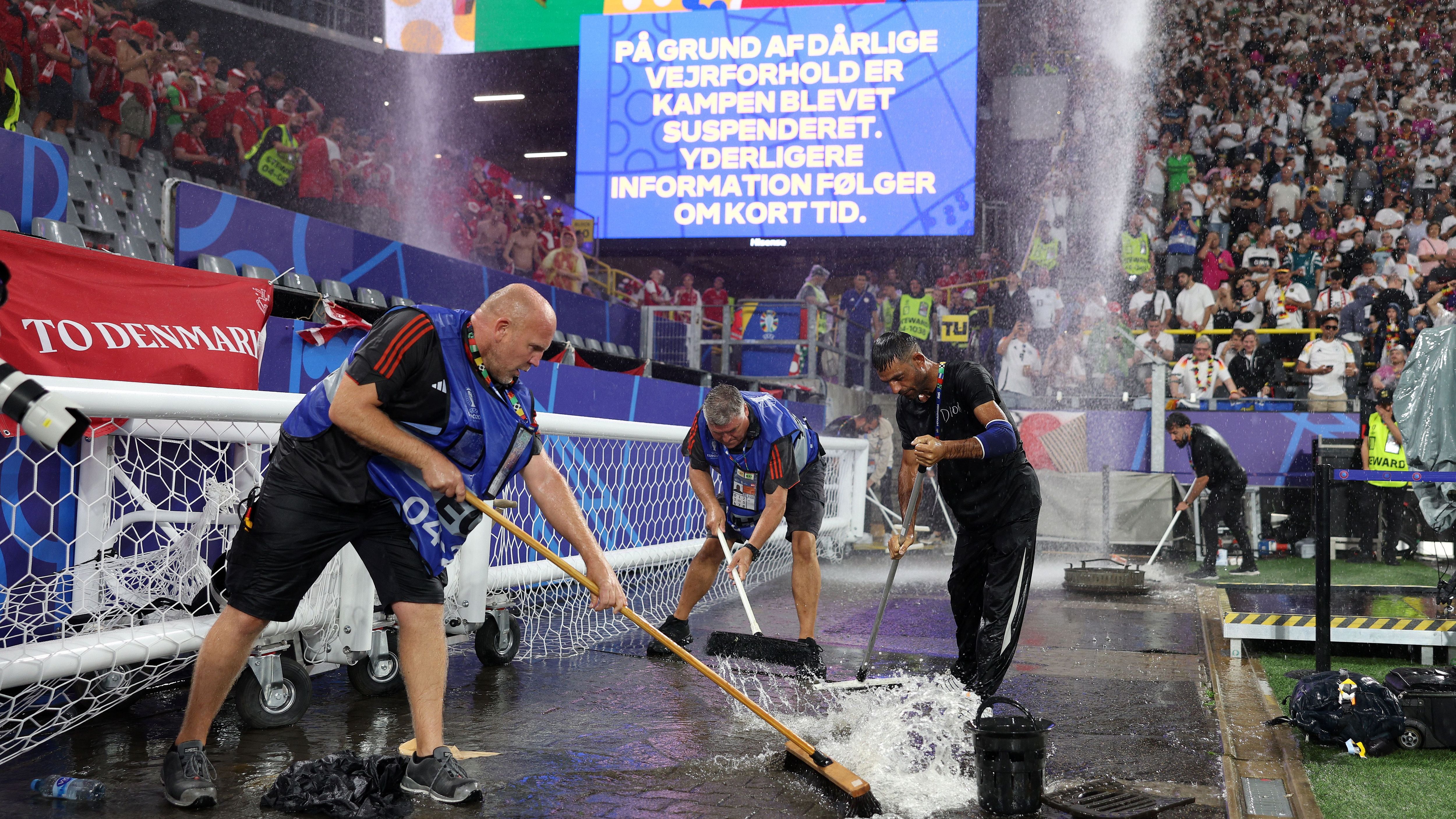 <strong>Voller Einsatz für die Spielfortsetzung</strong><br>Zahlreiche Helfer im Stadion versuchten ihr Bestes, um das sich ansammelnde Regenwasser vor der Tribüne in einen Abwasserkanal zu befördern.