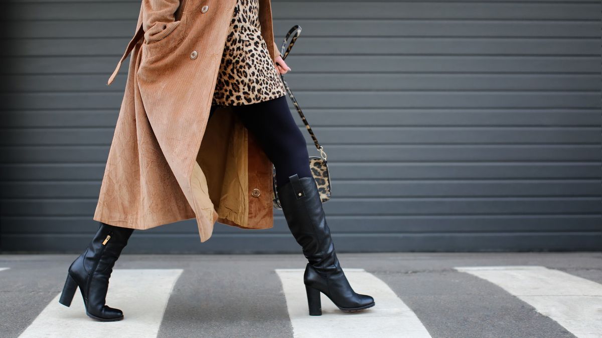 Stylish woman in black shoes walking across the street