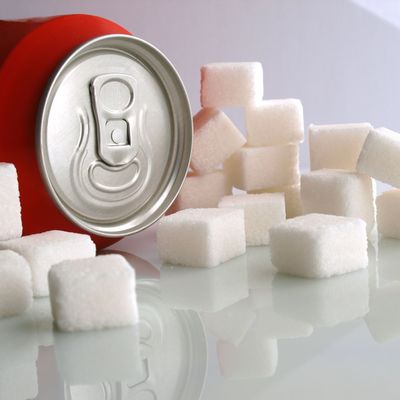 sugar addiction: sweet soda can and sugar cubes over white cold background