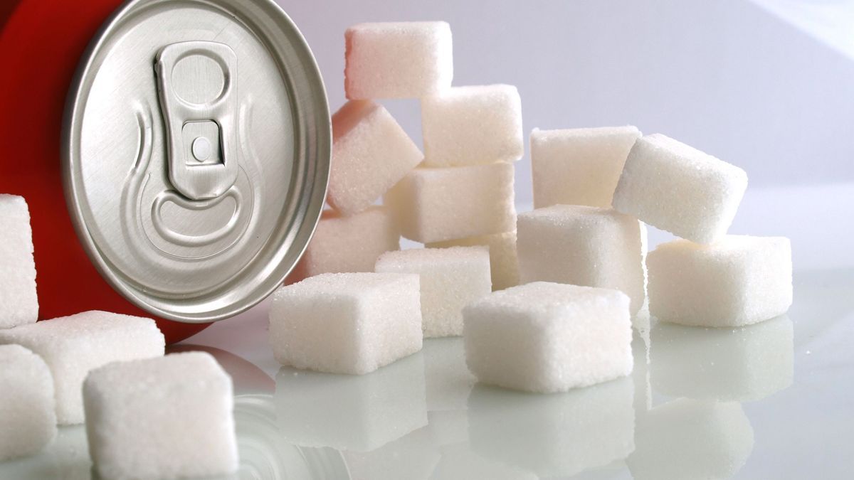 sugar addiction: sweet soda can and sugar cubes over white cold background