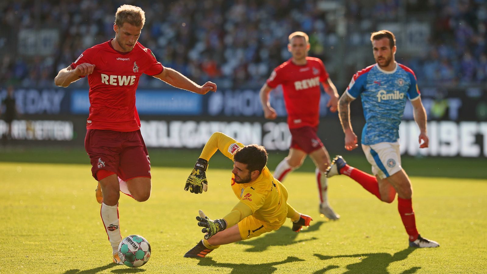 
                <strong>2021: 1. FC Köln vs. Holstein Kiel</strong><br>
                Die Kölner verloren zunächst zuhause gegen Holstein Kiel mit 0:1, doch damit waren die Domstädter noch lange nicht geschlagen. Im Rückspiel trumpften die Elf um Doppeltorschütze Sebastian Andersson (li.) in Kiel auf und schoss den Zweitliga-Dritten mit 5:1 ab. Schon zur Pause des Rückspiels führte die Mannschaft von Trainer Friedhelm Funkel mit 4:1. Damit schaffte der FC den Klassenerhalt doch noch auf den letzten Drücker über die Relegation. Für Kiel war auch beim zweiten Anlauf in der Relegation Endstation für die Bundesliga-Hoffnungen.
              