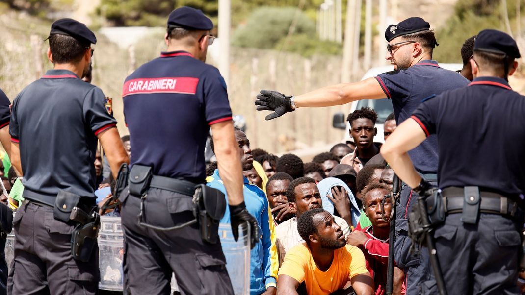 Italien, Lampedusa: Italienische Carabinieri sprechen mit Migranten, die in einem Aufnahmezentrum protestieren. 
