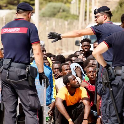 Italien, Lampedusa: Italienische Carabinieri sprechen mit Migranten, die in einem Aufnahmezentrum protestieren. 