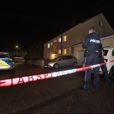 Polizisten stehen vor dem Mehrfamilienhaus, in dem drei Menschen erschossen wurden. 