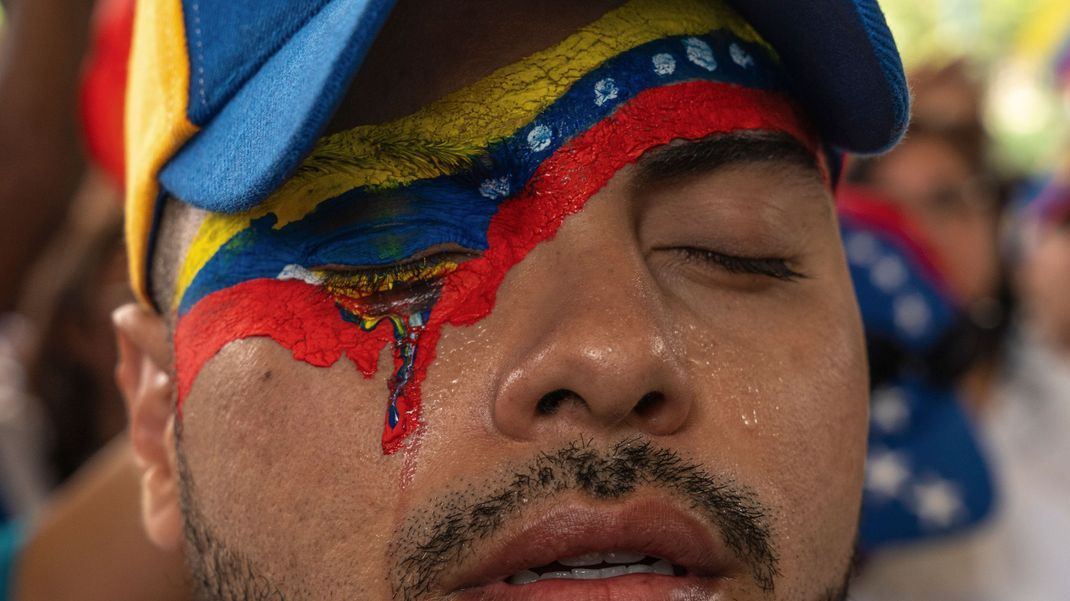 Ein venezolanischer Staatsbürger nimmt mit dem in den venezolanischen Nationalfarben bemalten Gesicht an einer Kundgebung in Panama-Stadt teil, um die nach Ansicht der Bevölkerung gefälschten Ergebnisse der Präsidentschaftswahlen anzuprangern, aus denen Präsident Maduro als Sieger hervorgegangen ist. 