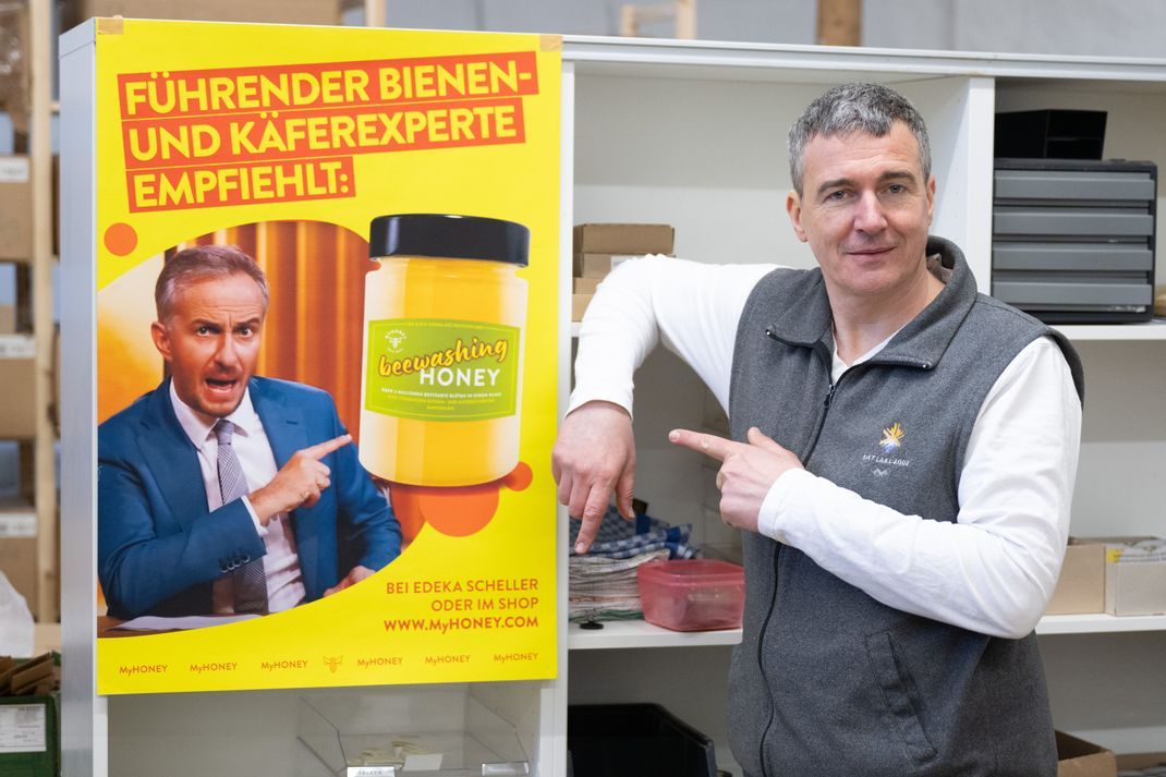 Imker Rico Heinzig steht neben einem Plakat mit dem Foto des Moderators Jan Böhmermann.
