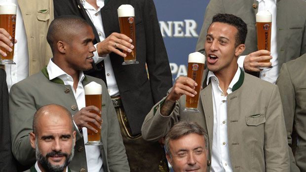 
                <strong>Costa beobachtet</strong><br>
                Für Neuzugang Douglas Costa ist die bayerische Tradition wahrscheinlich eine große Unbekannte. Im klassischen Trachten-Look macht der Brasilianer dennoch eine gute Figur. Und wie man mit Bier in der Hand vor der Kamera posiert, schaut sich Costa einfach bei Thiago (re.) ab.
              