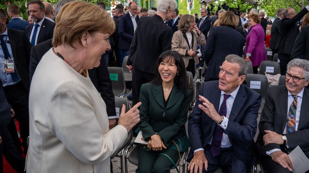Angela Merkel begrüßt So-yeon Schröder-Kim und Gerhard Schröder.