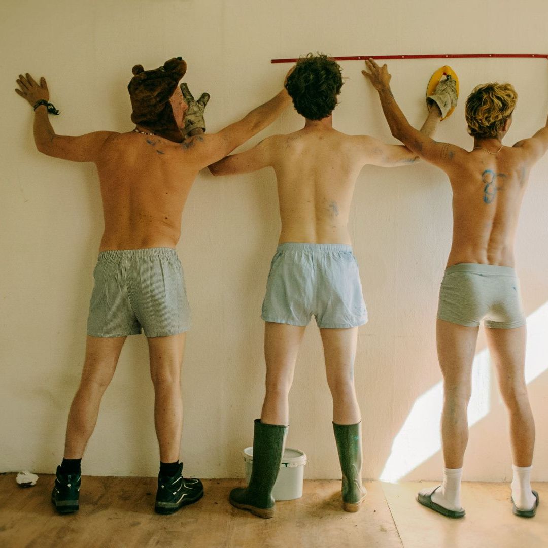 Carlo (Jeremias Meyer, M.), BlaBla (Sebastian Jakob Doppelbauer, l.) und Aydin (David Ali Rashed, r.) messen die Wand im besetzten Haus aus, während sie an der Renovierung arbeiten.