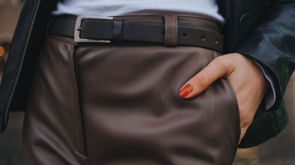 A woman holds her hands in the pocket of her pants. Elegant fashionable woman posing