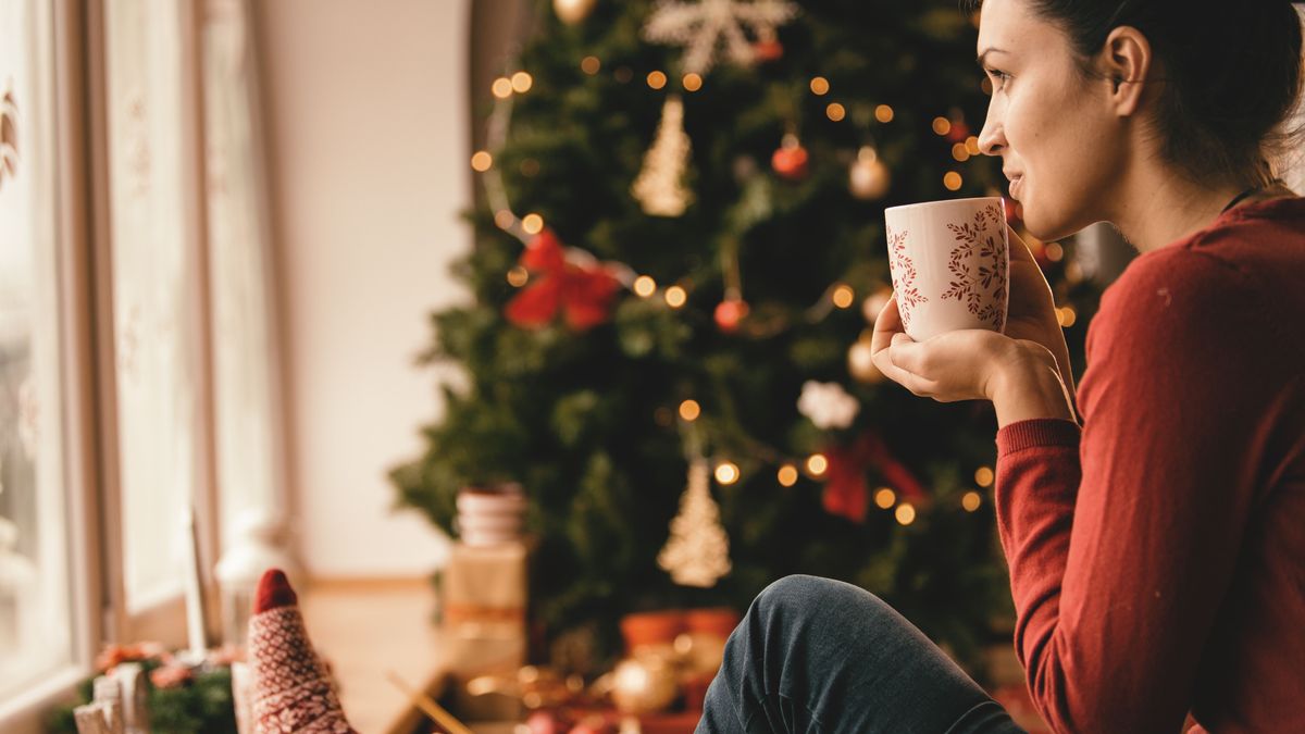 Frau mit Tasse in der Hand am Weihnachtsbaum