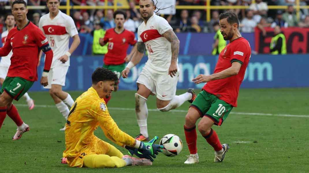 Torhüter Altay Bayindir von der Türkei (M) und Portugals Bernardo Silva kämpfen um den Ball.