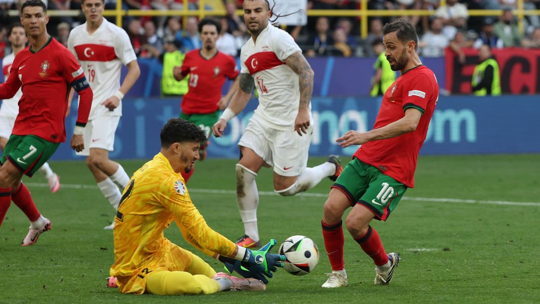 Torhüter Altay Bayindir von der Türkei (M) und Portugals Bernardo Silva kämpfen um den Ball.