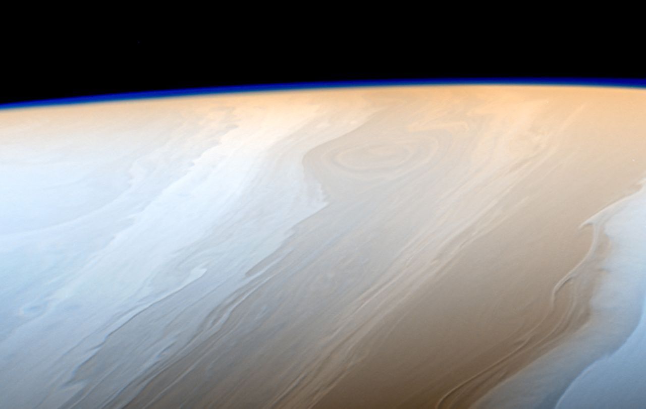 In dieser Aufnahme aus über einer Million Kilometer Entfernung als blaues Band am Horizont gut zu erkennen: Saturns Atmosphäre. Cassini flog bei anderen Gelegenheiten bis zu 3000 Kilometer nah an den Riesen heran. 