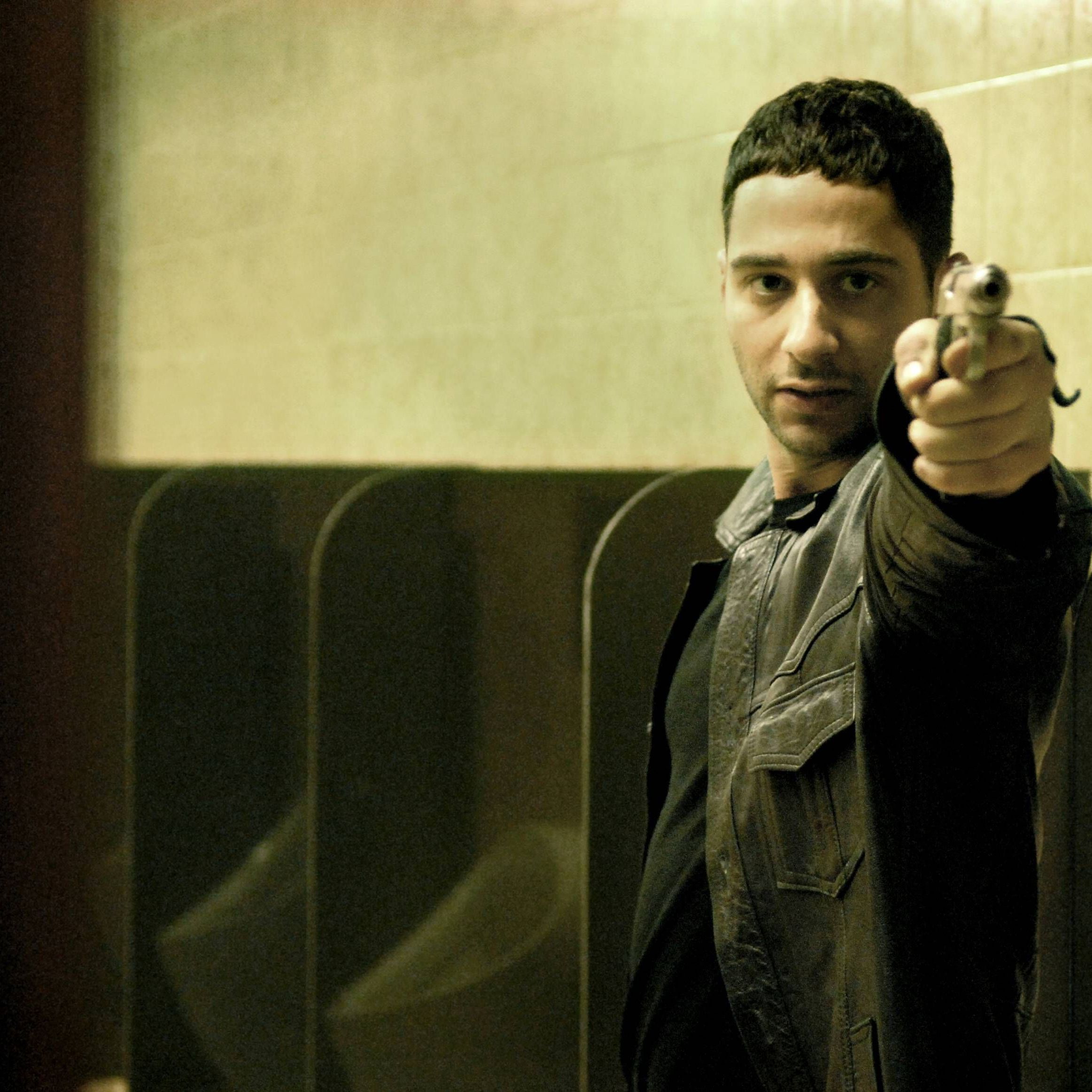 Denis Moschitto als Chiko, in dem gleichnamigen Film von Özgür Yildirim, der auf einer Toilette mit einer Waffe auf jemanden zielt.