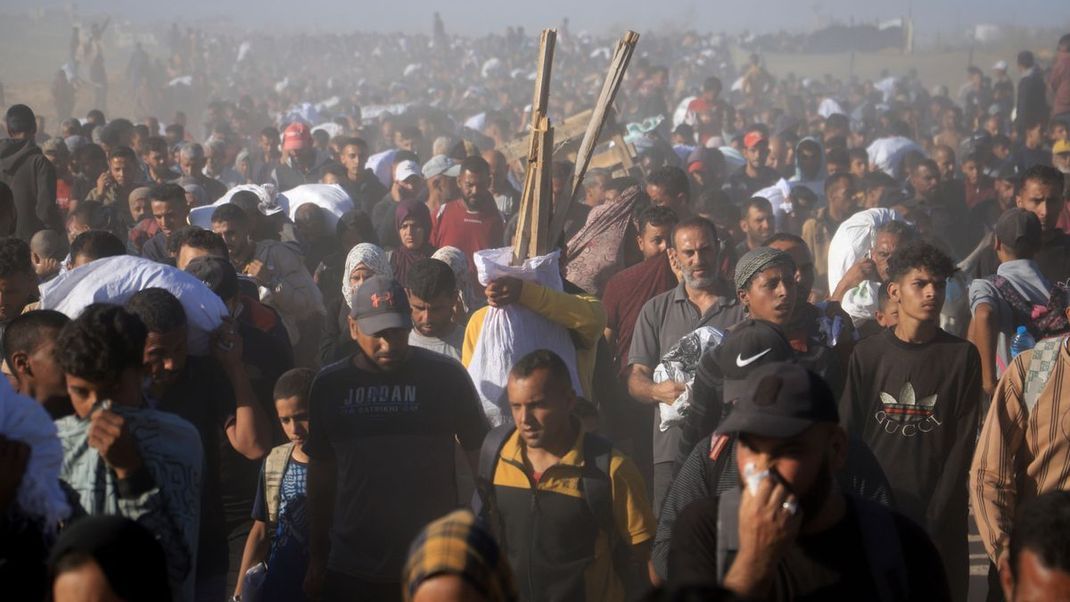 Palästinenser:innen tragen Kisten und Taschen mit Lebensmitteln und humanitären Hilfspaketen - dabei sollen sieben von ihnen durch das israelische Militär getötet worden sein. (Symbolbild)