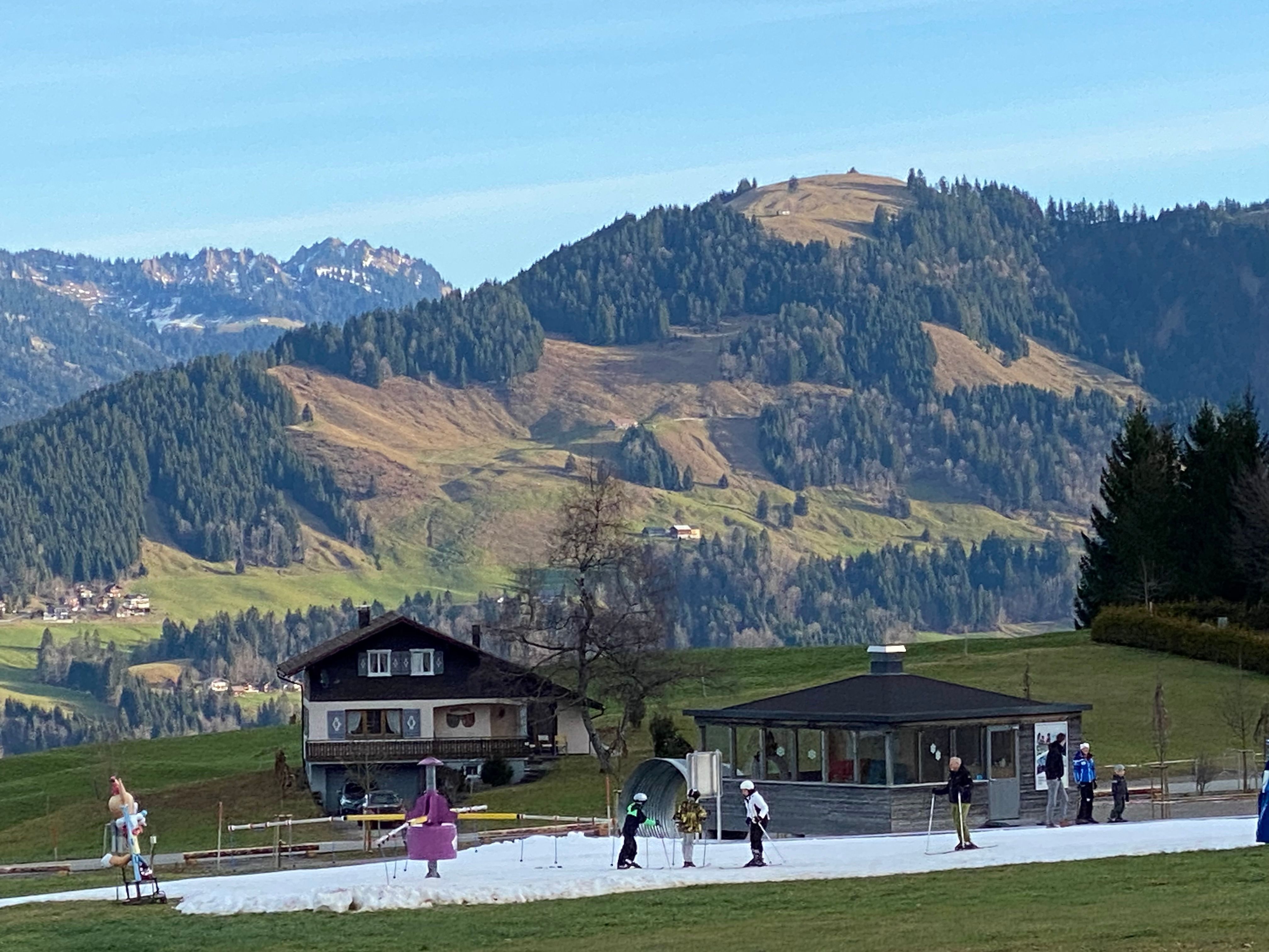Österreich, Schetteregg: Auf einem Flecken, der künstlich mit Schnee präpariert wurde, üben Anfänger im Skigebiet die ersten Schritte auf Skiern. Für die Jahreszeit ist es hier derzeit viel zu warm.