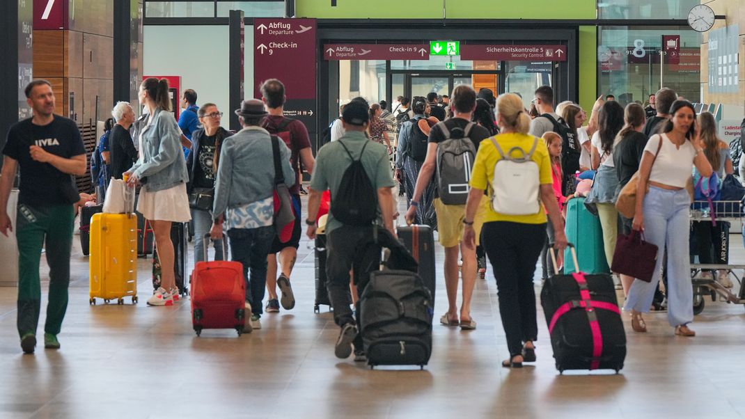 Archivbild - 13.07.2023, Brandenburg, Schönefeld: Reisende gehen auf dem Flughafen Berlin Brandenburg BER "Willy Brandt" am ersten Sommerferientag in Berlin und Brandenburg durch Terminal 1.