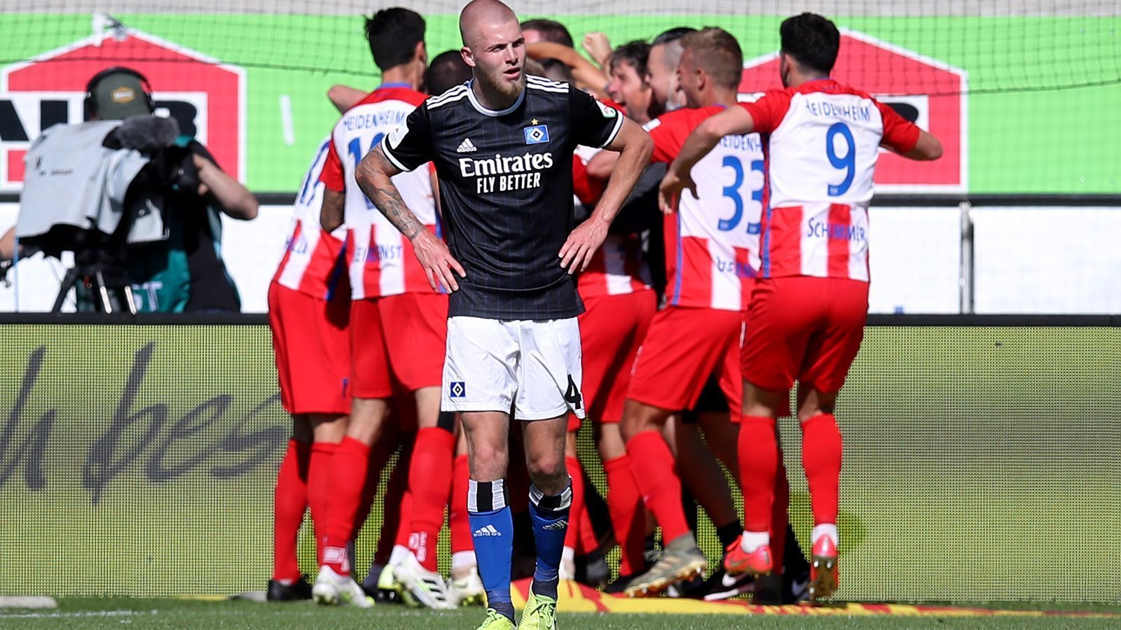 
                <strong>Sonntag, 28. Juni 2020</strong><br>
                Fußball-Deutschland schaut - mal wieder - auf den HSV: Nach dem Drama gegen Heidenheim sind die Hamburger auf Schützenhilfe von Bielefeld angewiesen, um doch noch Dritter zu werden. Heidenheim spielt bei der schon aufgestiegenen Arminia und steht vor dem größten Erfolg der Vereinsgeschichte. Derzeit hat der HSV einen Punkt Rückstand auf den FCH, weist aber das deutlich bessere Torverhältnis auf. Im Abstiegskampf könnte Greuther Fürth seinen Erzrivalen Nürnberg in den Abgrund reißen. Wenn die Fürther gegen den KSC verlieren und der "Club" nicht in Kiel gewinnt, muss Nürnberg in die Abstiegsrelegation.
              