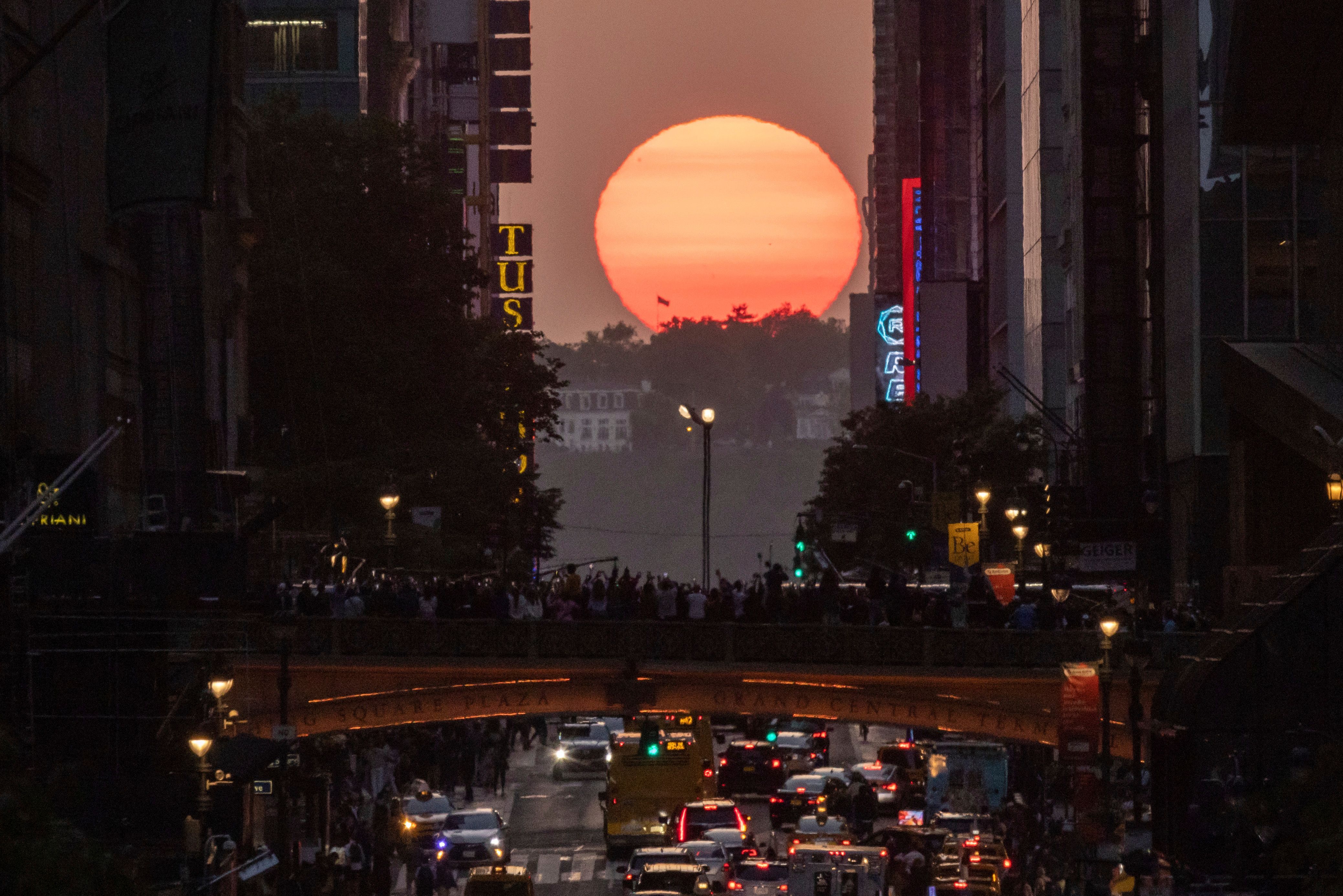 30. Mai 2023: Menschen beobachten den Sonnenuntergang auf der 42. Straße in New York, während eines Phänomens, das als "Manhattanhenge" bekannt ist.