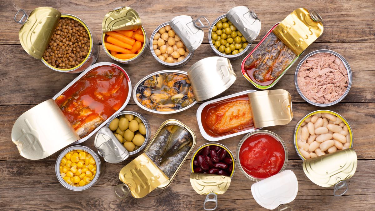 Canned food on wooden background, top view