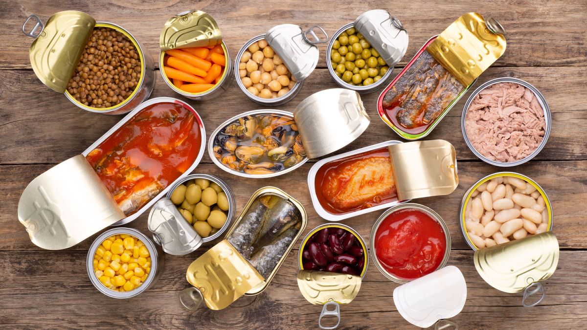 Canned food on wooden background, top view