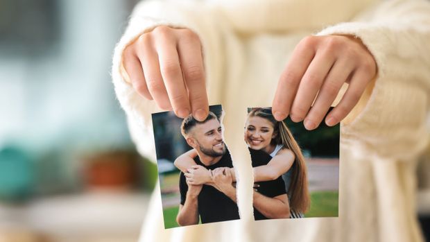 Woman tearing up photo of happy couple, closeup. Concept of divorce