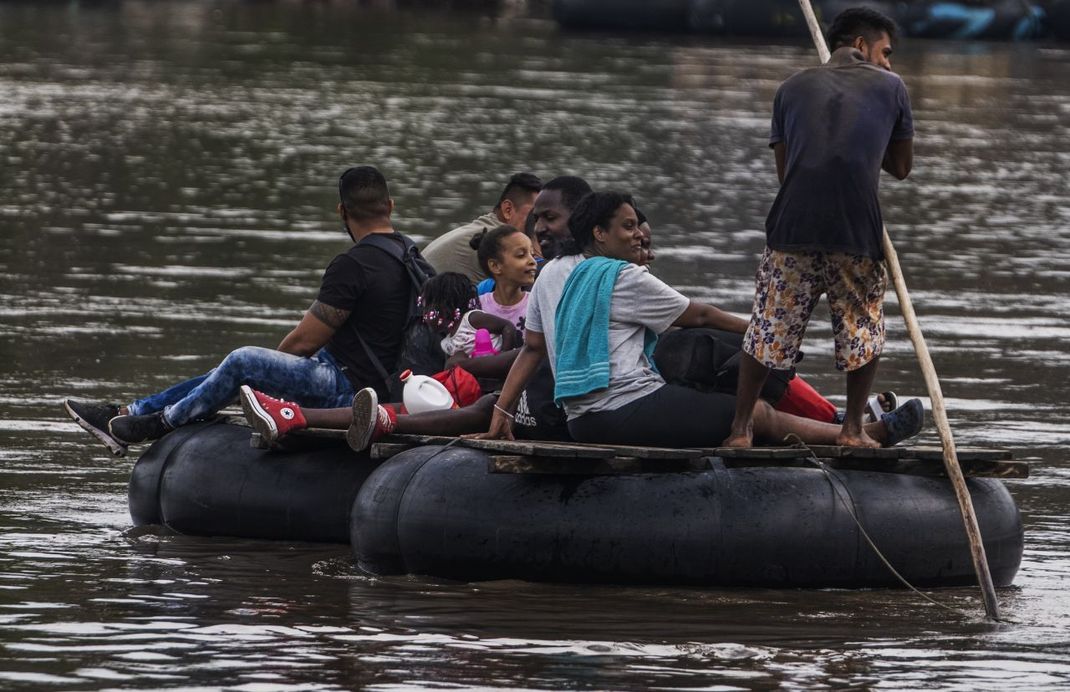 Eine haitianische Familie überquert auf einem behelfsmäßigen Schlauchboot einen Fluss von Guatemala nach Mexiko.