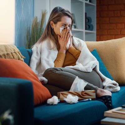 Woman with cold and flu blowing her nose