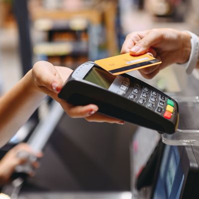 Cropped close up woman hand arm shopping at supermaket put credit card to wireless modern bank payment terminal process acquire payments near cashier checkout inside store. People purchasing concept.