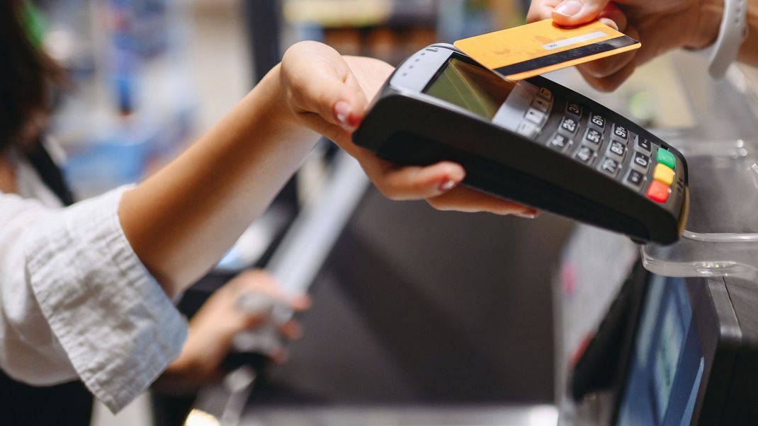 Cropped close up woman hand arm shopping at supermaket put credit card to wireless modern bank payment terminal process acquire payments near cashier checkout inside store. People purchasing concept.