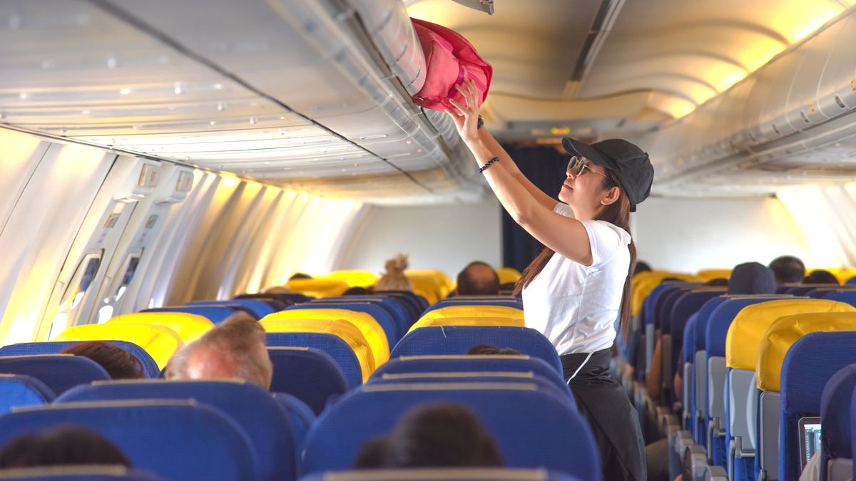 woman passenger traveler on boarding aircraft looking for empty overhead locker for luggage keep in safe on the flight