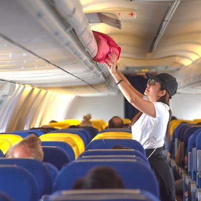 woman passenger traveler on boarding aircraft looking for empty overhead locker for luggage keep in safe on the flight