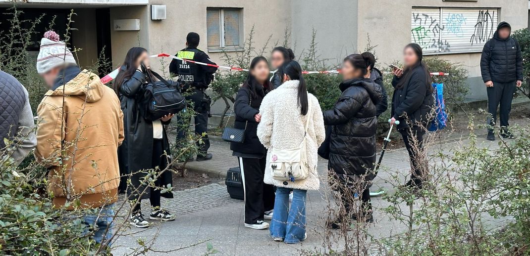 28.02.2024, Berlin: Anwohner stehen vor dem Wohnhaus der früheren RAF-Terroristin Daniela Klette, das wegen einer möglichen Gefahr geräumt wurde. 