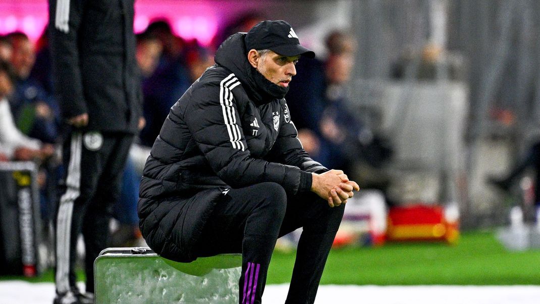 Während dem Spiel des FC Bayern München gegen RB Leipzig sitzt Trainer Thomas Tuchel auf einem zerbeulten Metallkoffer.