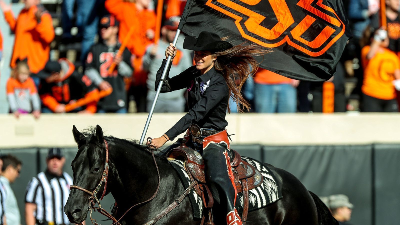 
                <strong>Bullet und der OSU Rider</strong><br>
                Seit 1984 gibt es das "Spirit Rider"-Programm. Der ehemalige Professor für Landwirtschaftslehre, Eddy Finley, wollte ein Maskottchen finden, das nach jedem Touchdown die Flagge über das Feld tragen konnte. Und was liegt da näher, als ein Cowboy oder Cowgirl im Sattel. Nach jedem Sechs-Punkte-Score stürmt der Spirit Rider bei einem Heimspiel auf das Feld zur 30-Yard-Linie und trägt stolz die OSU-Flagge zur Schau. Das Pferd mit dem Namen "Bullet" hat derweil sogar einen eigenen Stall im West-Abschnitt des Boone Pickens Stadium.
              