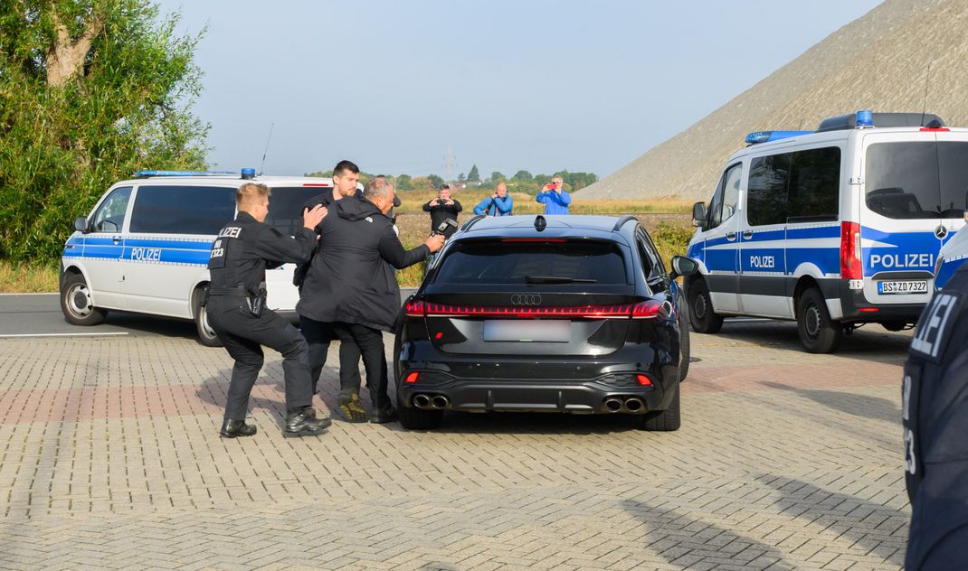 Polizisten stoppen einen Fotografen, als ein schwarzer Audi in Begleitung von Fahrzeugen der Polizei die Justizvollzugsanstalt (JVA) Sehnde verlässt. 