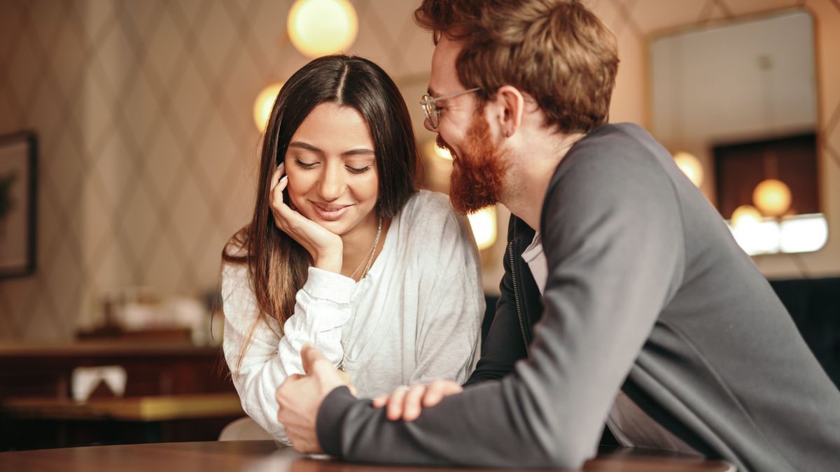 Multiethnic loving couple flirting in coffee shop