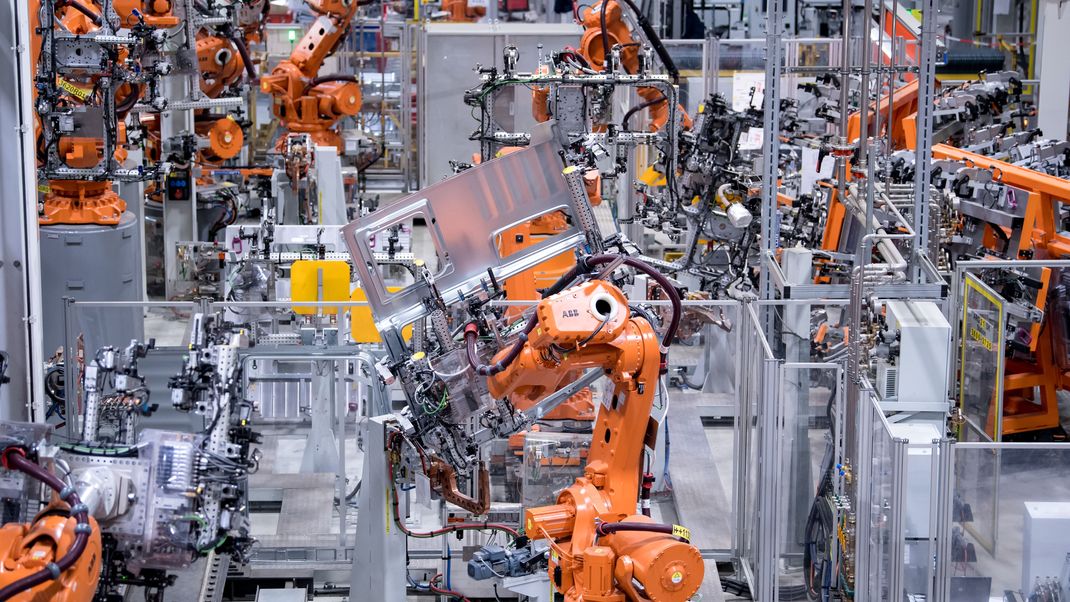 Roboter von ABB arbeiten bei MAN Truck & Bus in einer Werkshalle an Seitenwänden von Fahrerkabinen von Lastwagen.