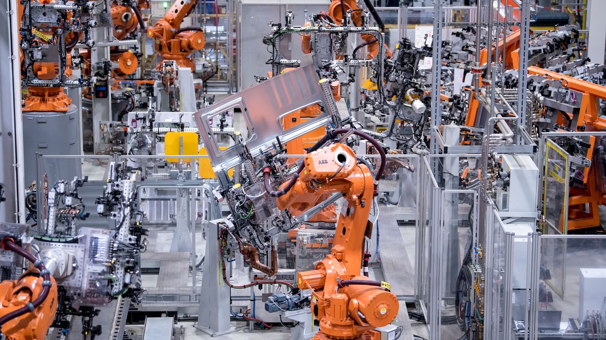 Roboter von ABB arbeiten bei MAN Truck & Bus in einer Werkshalle an Seitenwänden von Fahrerkabinen von Lastwagen.