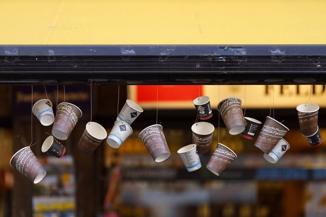 Take-Away-Regelungen statt Restaurantbesuch lassen während der Corona-Krise den Müll in Großstädten anwachsen, hier wiederverwertete Kaffeebecher als Girlande an einem Kiosk in Köln.