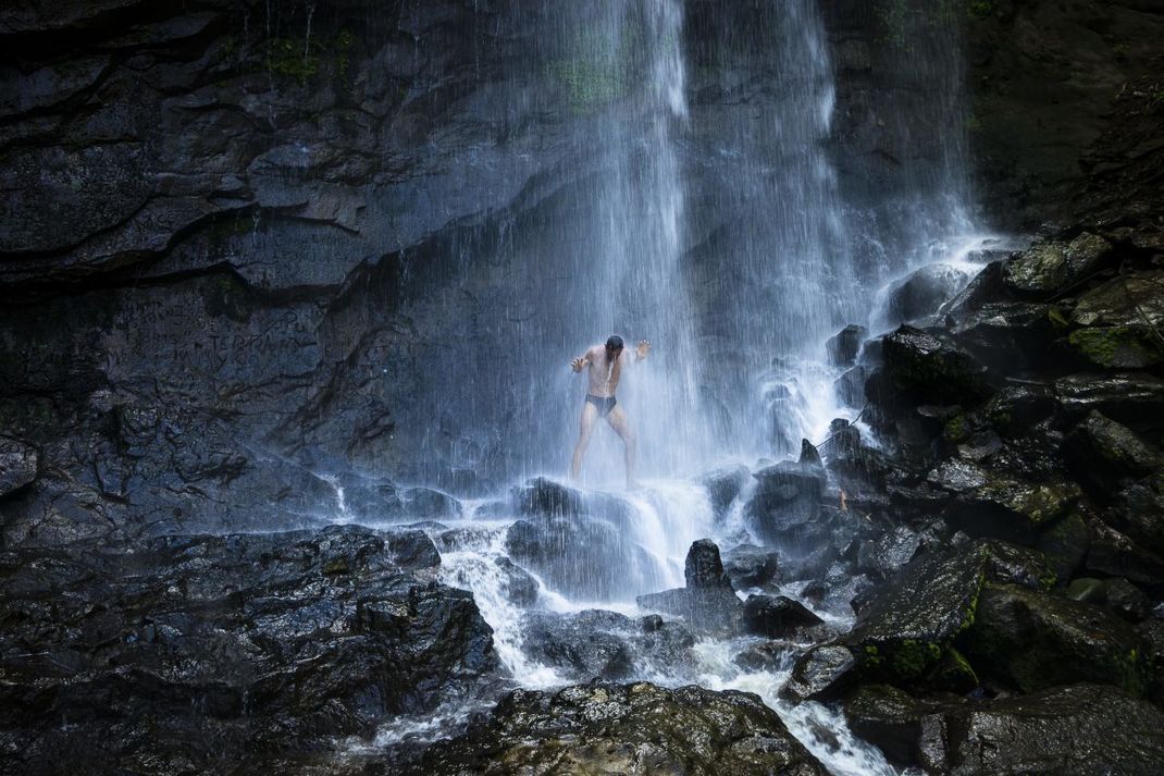 Ein Mann genießt die "natürliche Dusche" unter dem Concord-Wasserfall (Grenada).